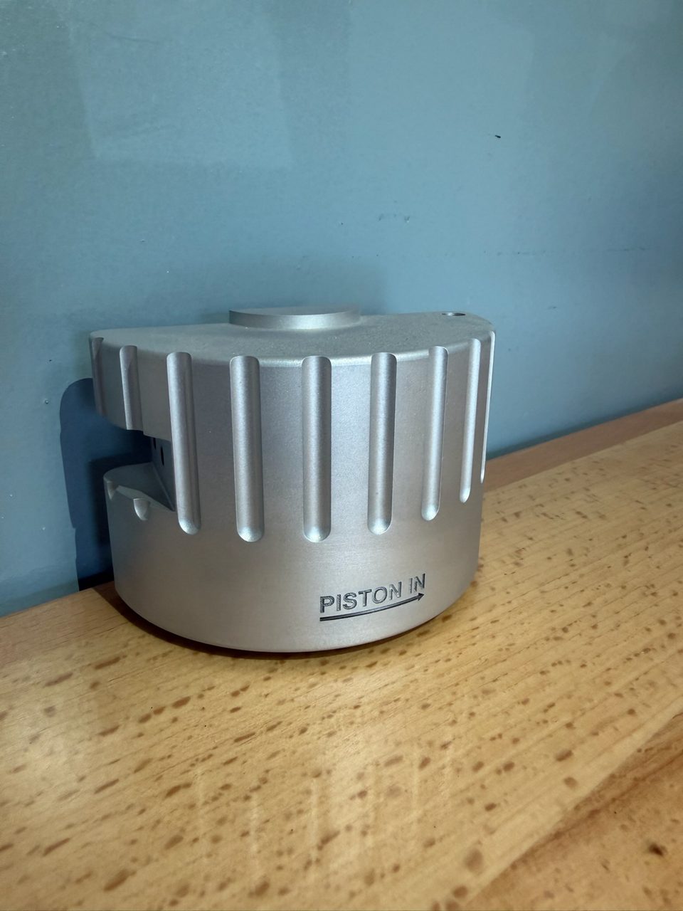 Machined aluminium housing laser engraved with the words PISTON IN and a direction arrow