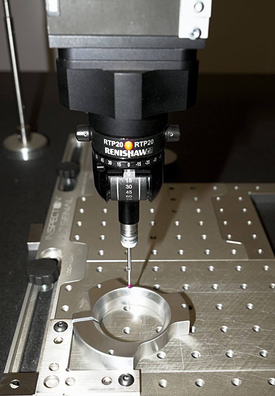 Coordinate measuring machine touch probe measuring a machined aluminium component on a fixture plate